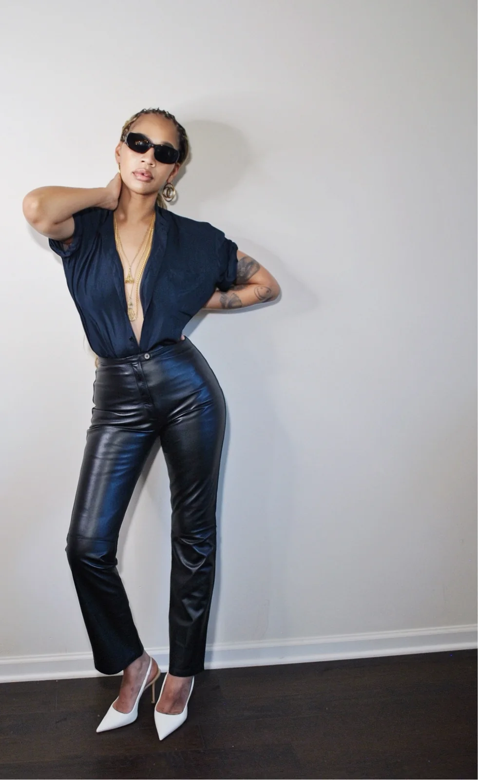 Navy short-sleeved shirt tucked into black leather pants with white slingback pumps