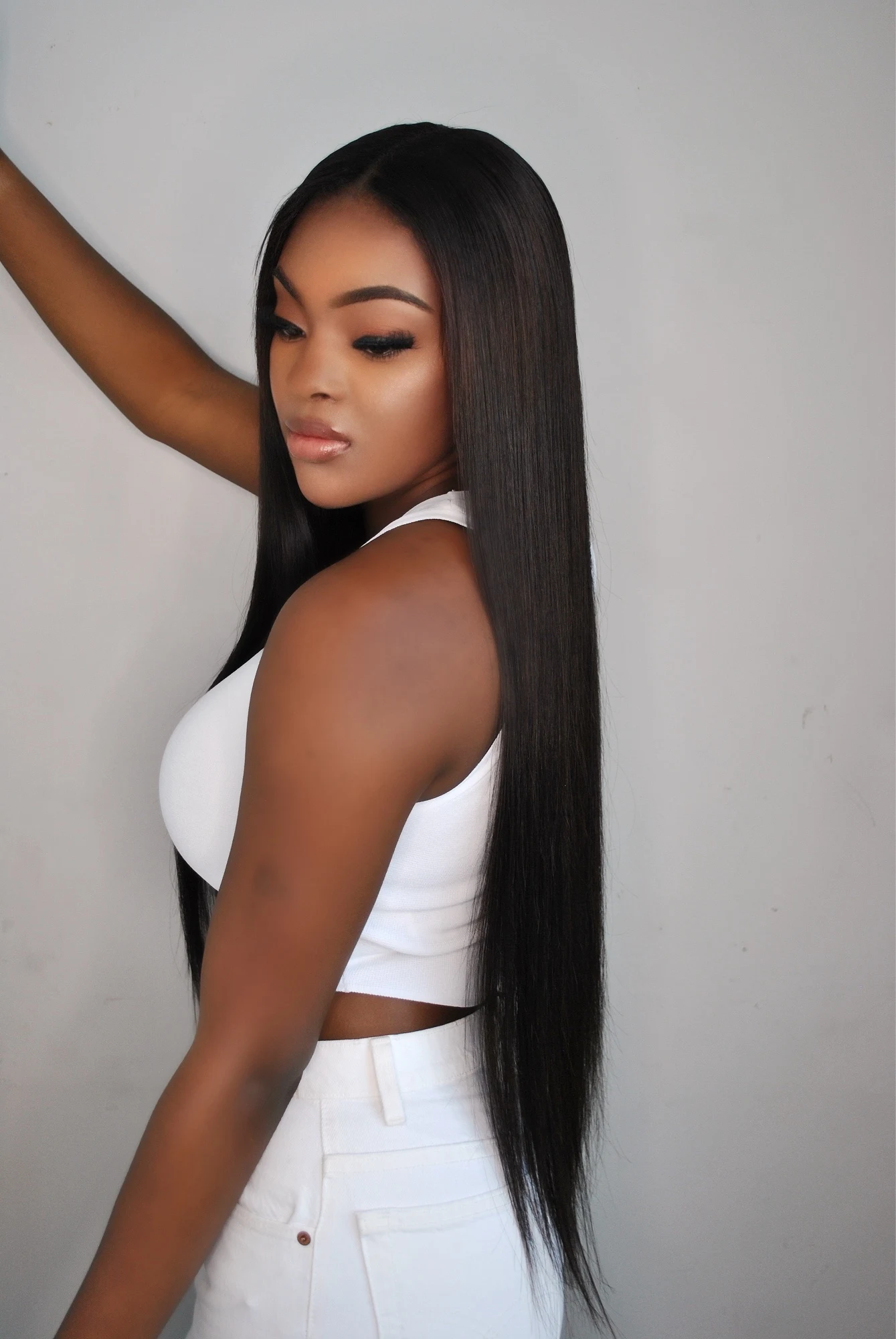 Side-profile portrait in a white cropped tank and white jeans with long straight hair
